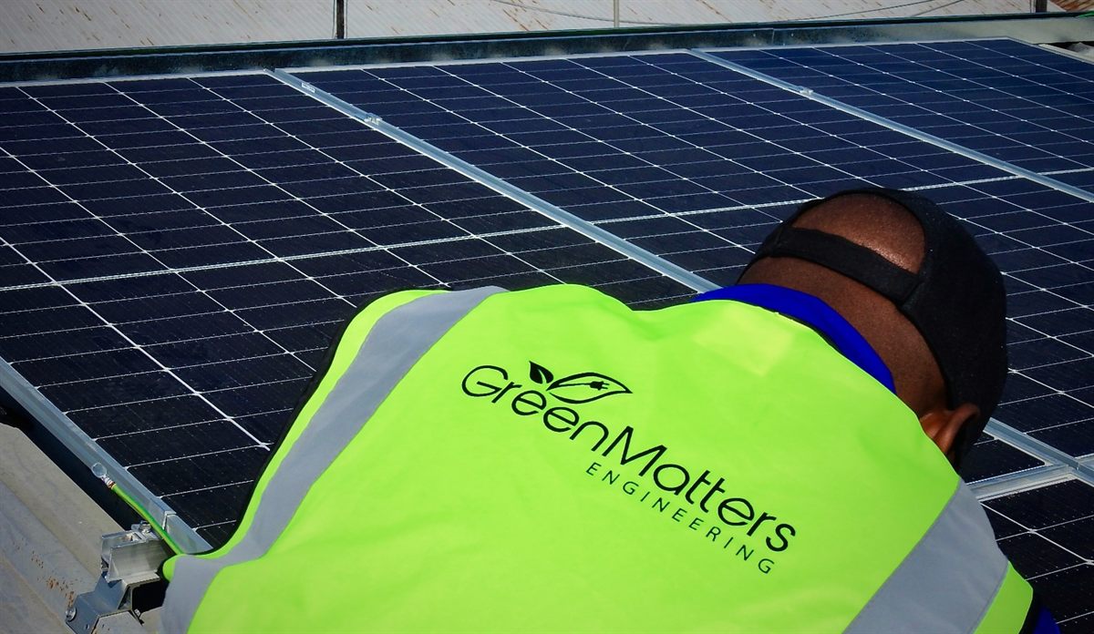 A GreenMatters engineer fitting solar panels on a commercial roof